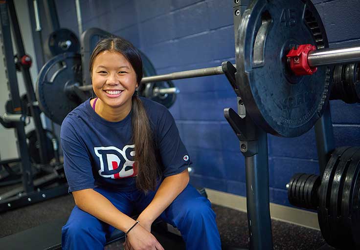 female student lifting weights in fitness center