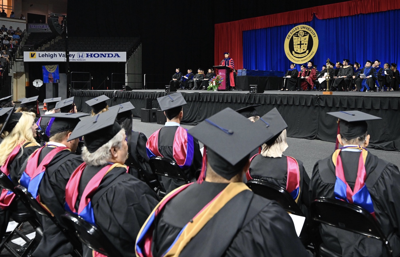 Father James Greenfield on stage and graduates in the crowd