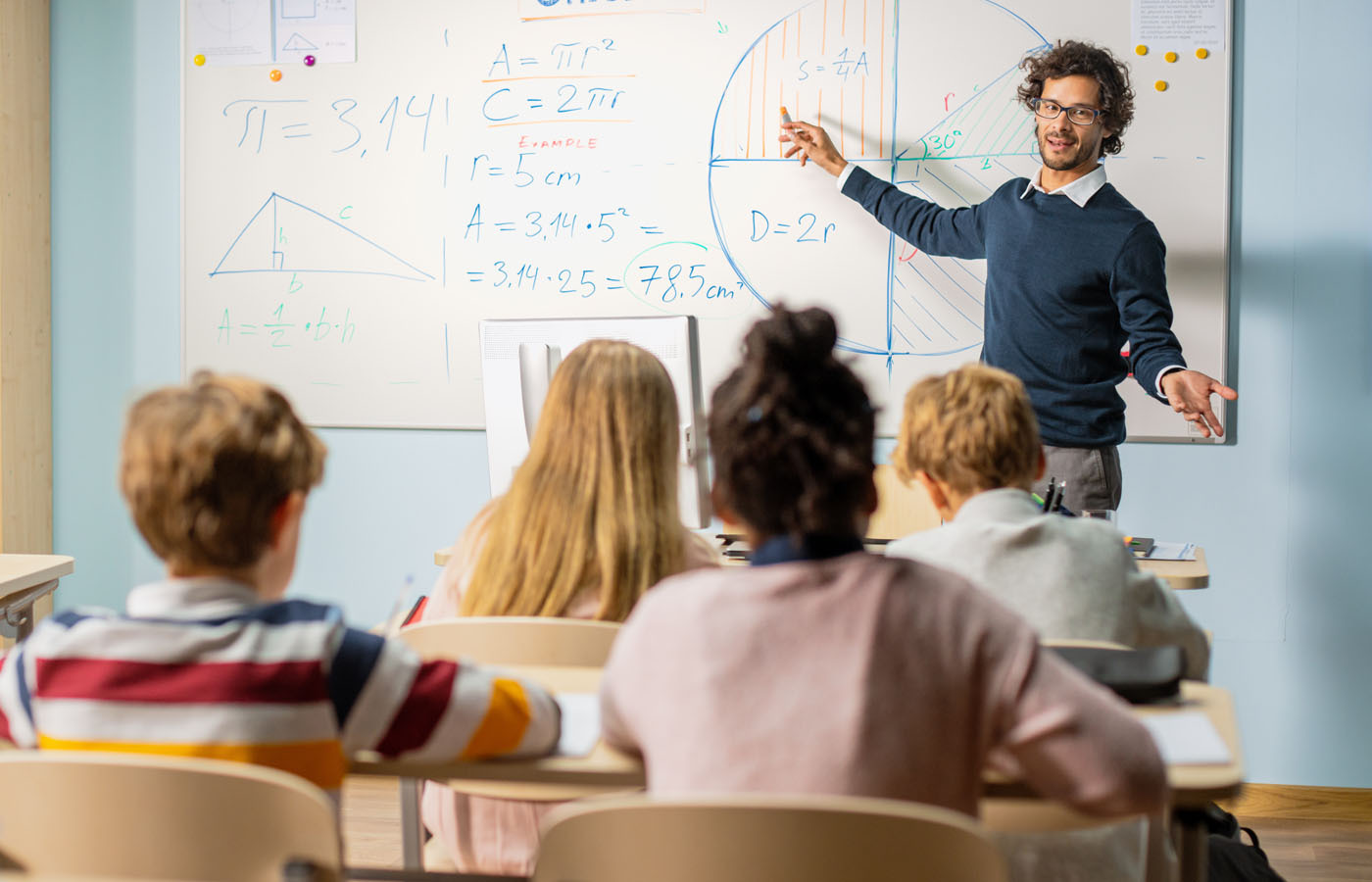 Generic teacher teaching at whiteboard in front of class