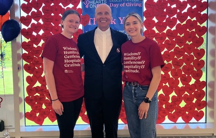 Father James Greenfield standing next to two students