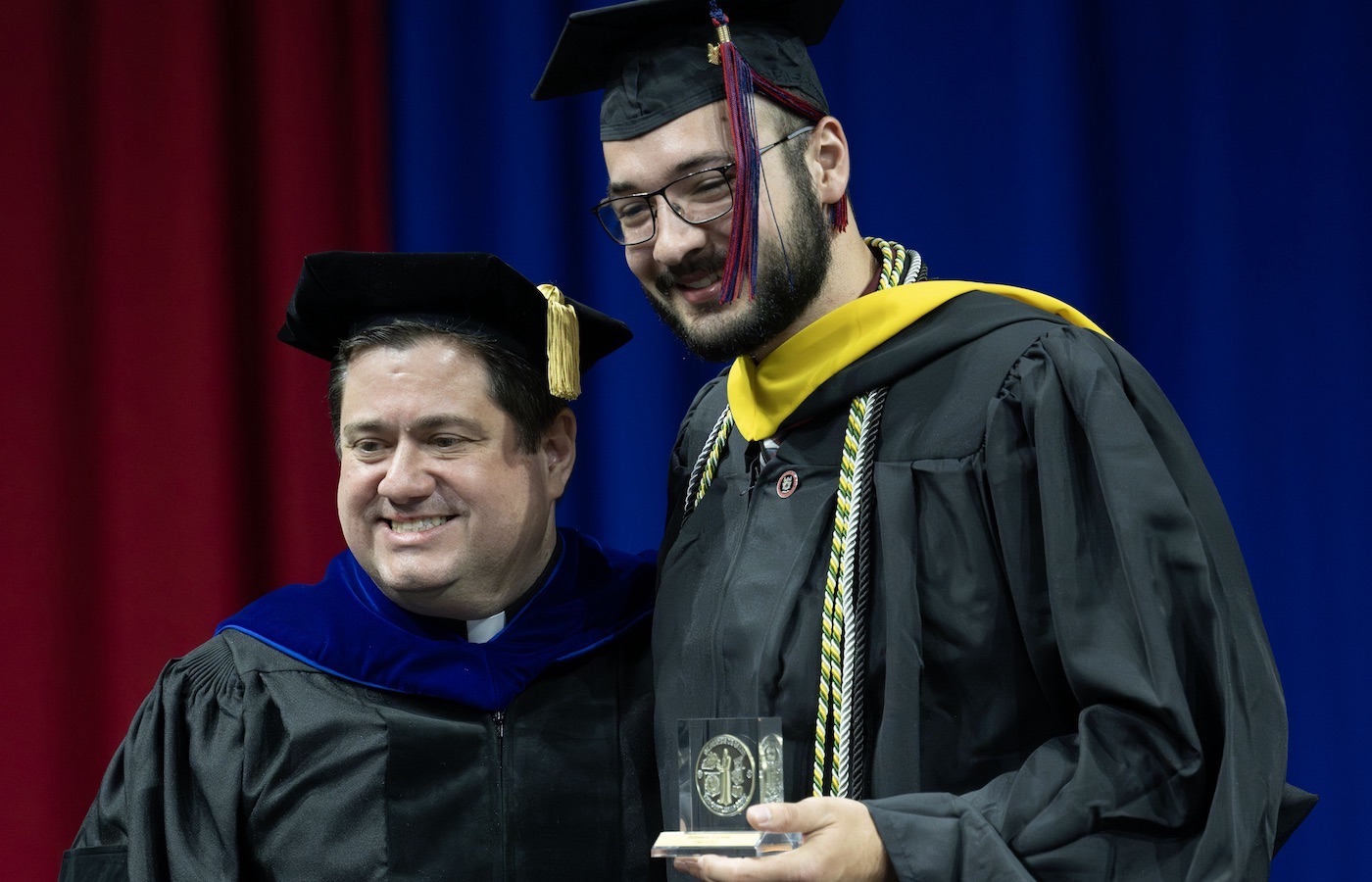 Very Rev. Jack Kolodziej and Jaimason Lacasse on stage at Commencement