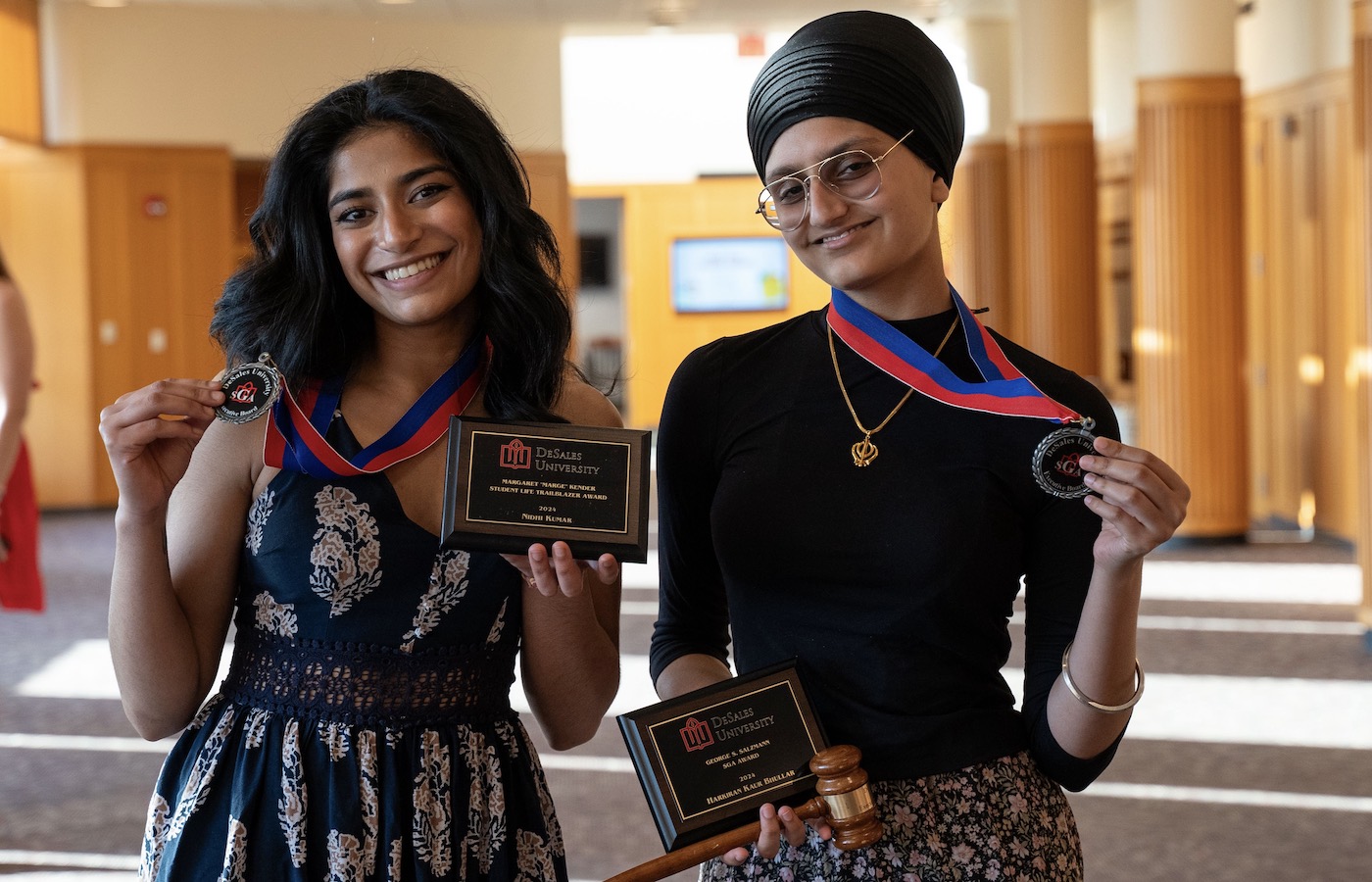 Nidhi Kumar and Harkiran Bhullar holding medals and plaques