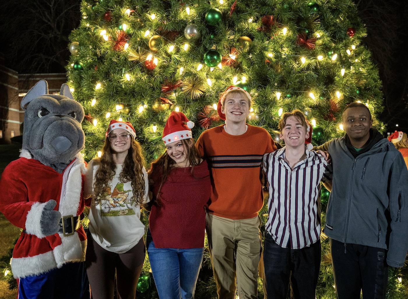 Students and Frankie in front of lit up Christmas tree